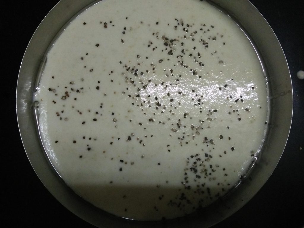 Dhokla batter put in a plate greased with oil and garnished with black pepper