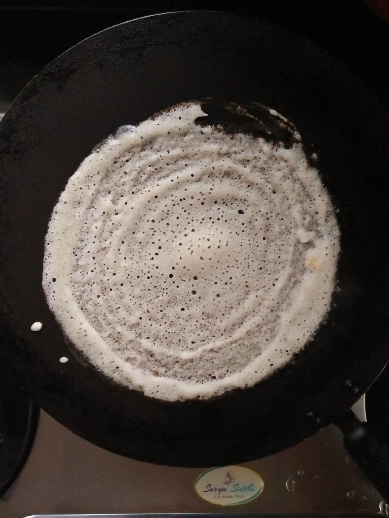 Dosa batter pouredd in a pan and then spread with ladle in a non stick pan